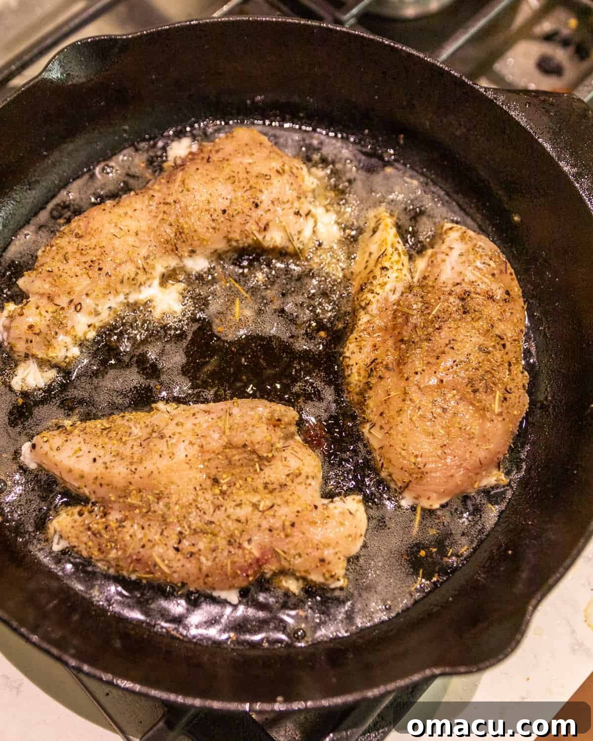 Chicken breasts sizzling and cooking in a hot skillet, developing a golden-brown crust and juicy interior.
