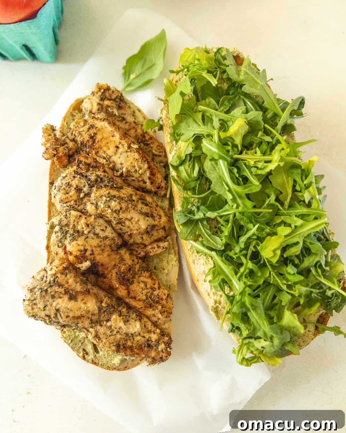 Tender slices of perfectly cooked chicken being carefully added as a foundational layer to the chicken caprese sandwich.