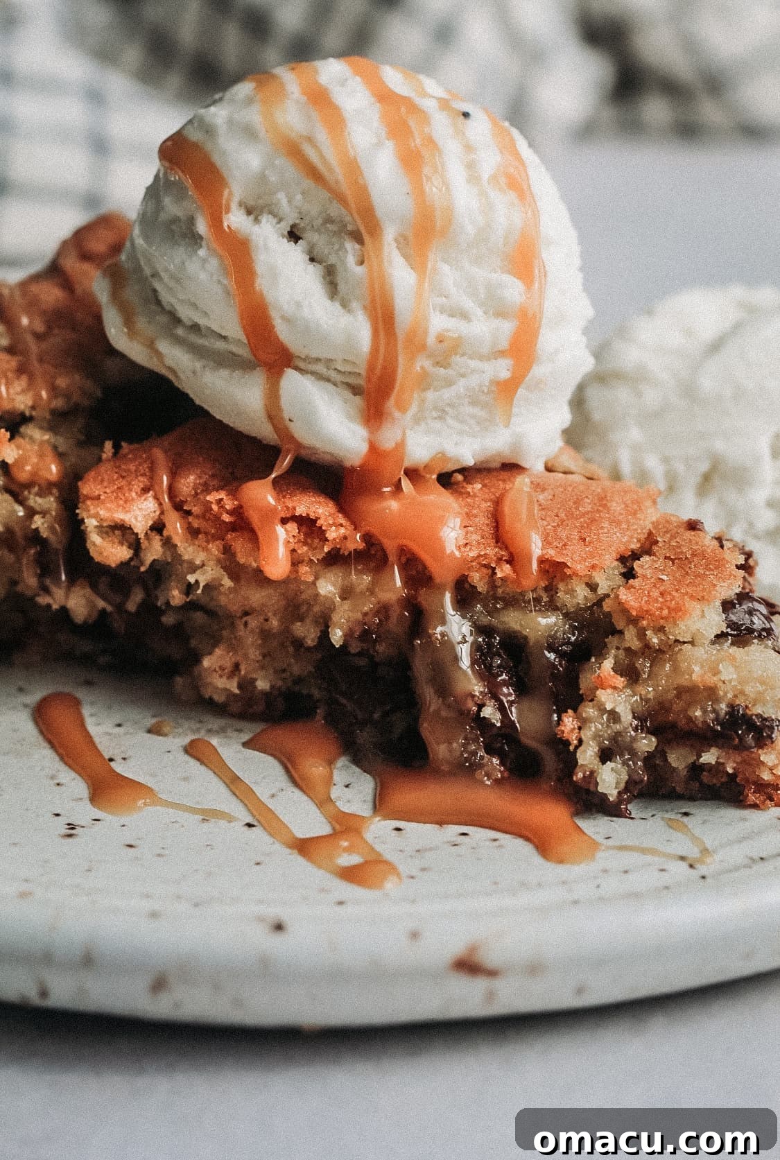 Warm Triple Chocolate Chip Skillet Cookie topped with scoops of melting vanilla ice cream.