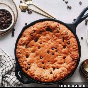 A baked chocolate chip skillet cookie in a cast iron pan.