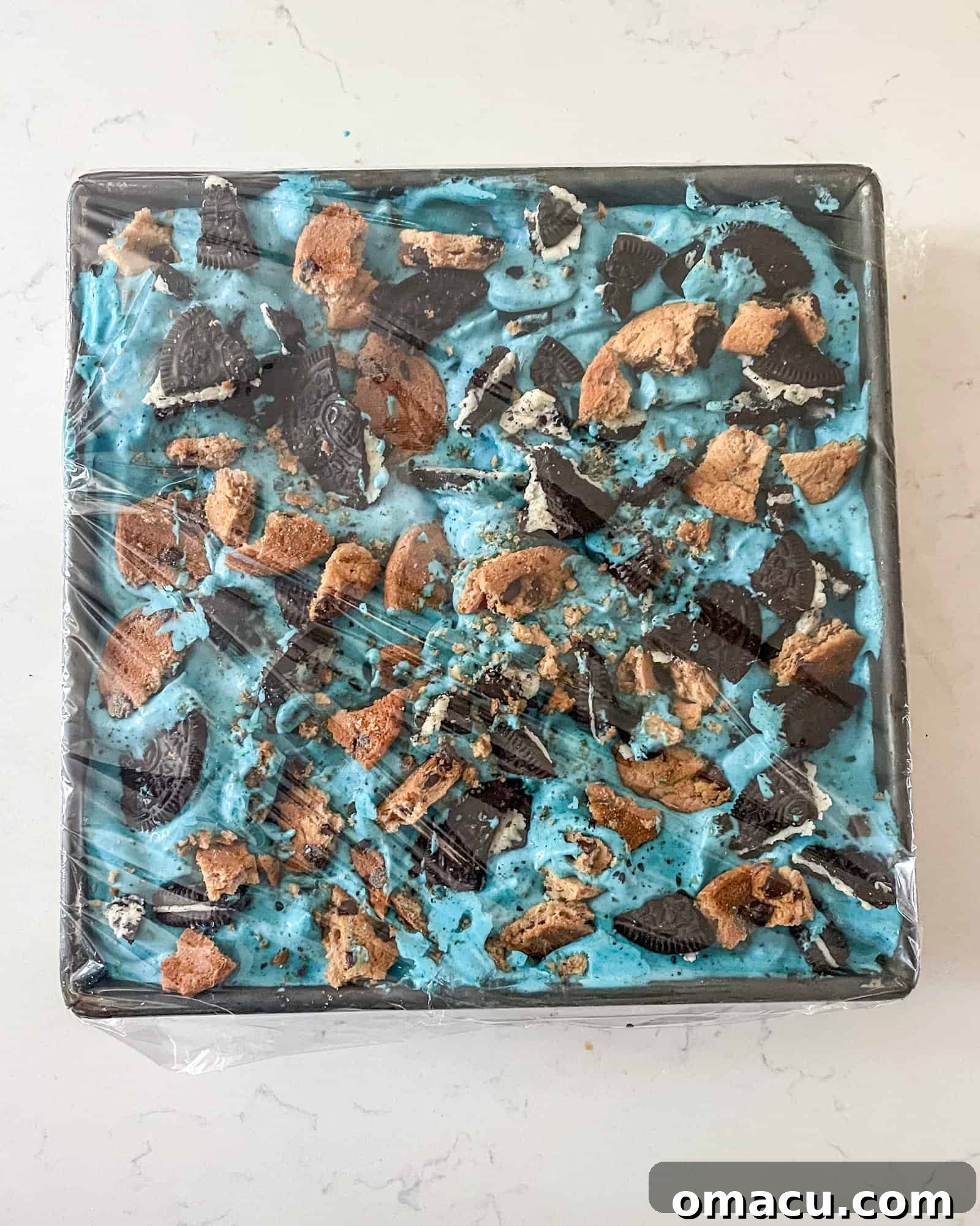 cookie monster ice cream in a freezer safe container covered with plastic wrap.