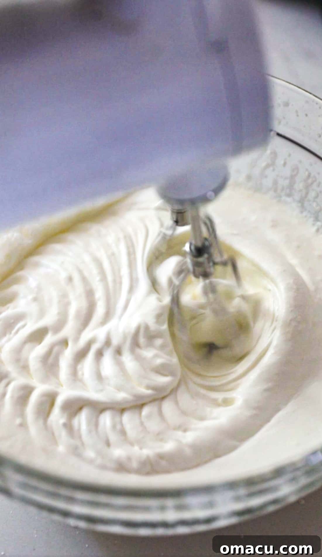 heavy whipping cream being beat with an electric mixer in a bowl to make whipped cream for the cookie monster ice cream.