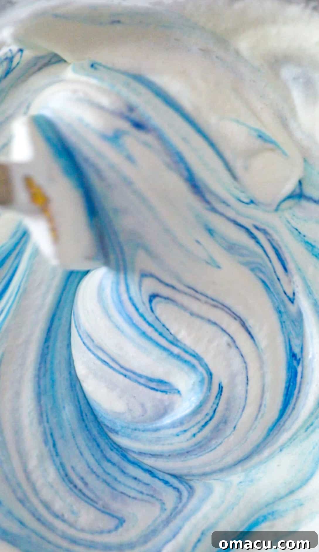 blue food coloring being added to the heavy whipping cream.