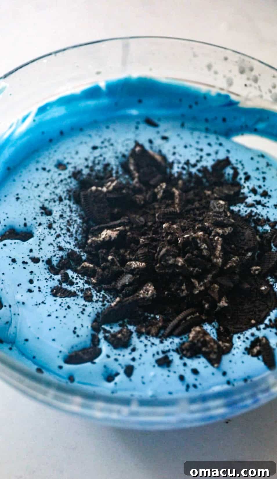 oreo cookies being folded into the blue whipped cream to make cookie monster ice cream.