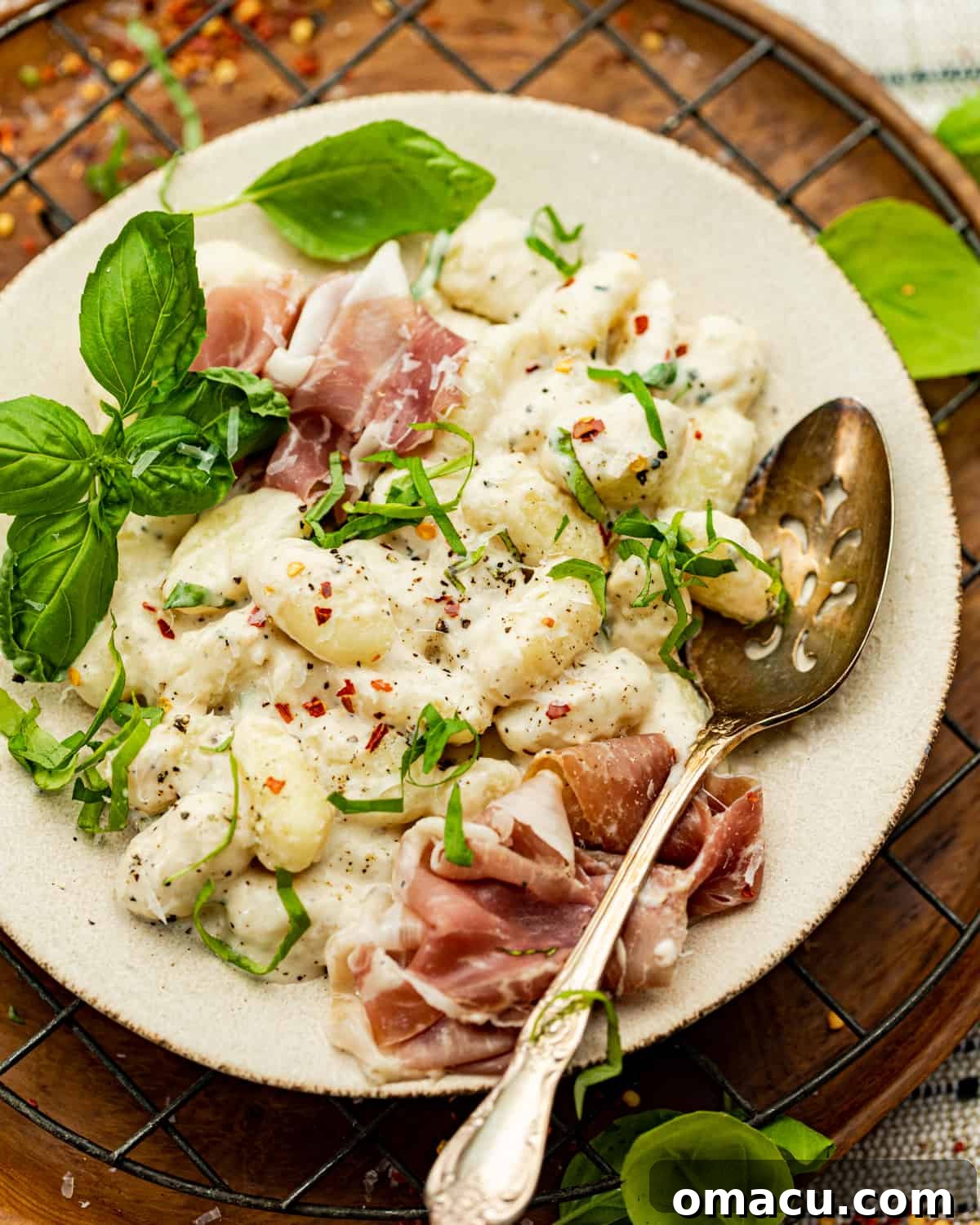 A serving of creamy cacio e pepe gnocchi on a plate with a spoon, ready to eat.
