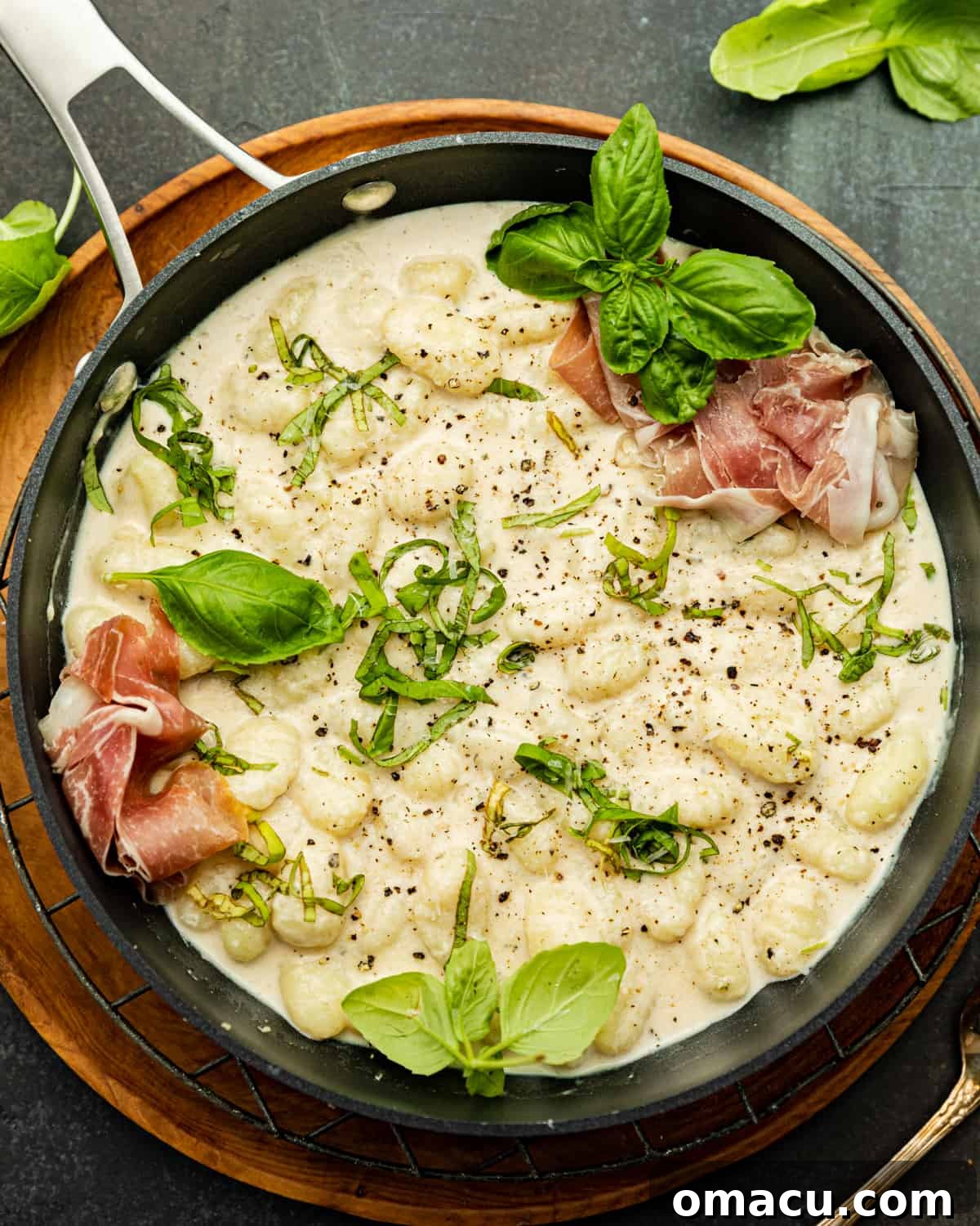 Creamy cacio e pepe gnocchi in a Calphalon pan placed on a wooden board.