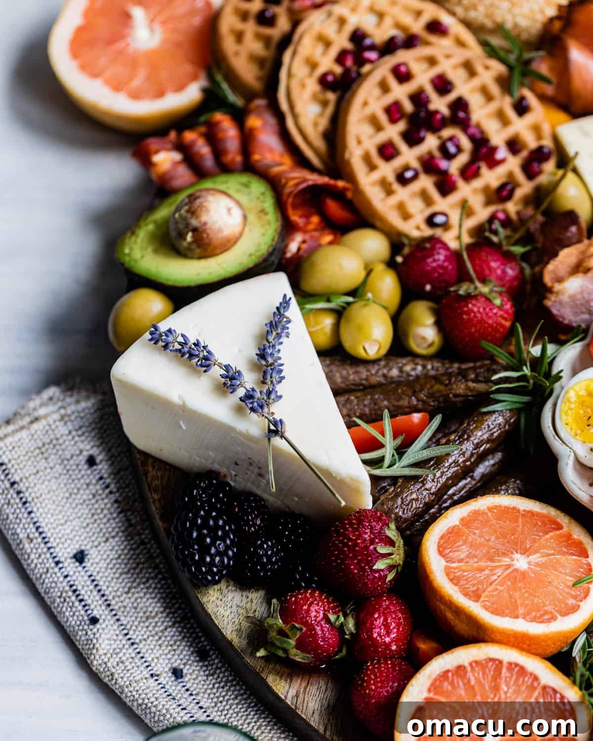 Assorted cheeses arranged on a cheese board, garnished with fresh lavender sprigs for an elegant touch.