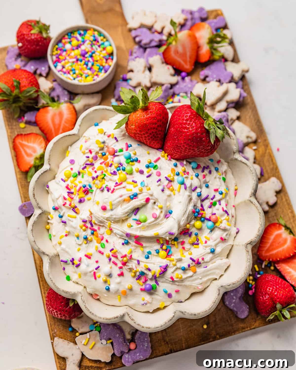 A beautifully arranged serving board featuring a bowl of homemade Dunkaroo Dip, accompanied by fresh strawberries and crispy animal crackers, perfect for sharing.