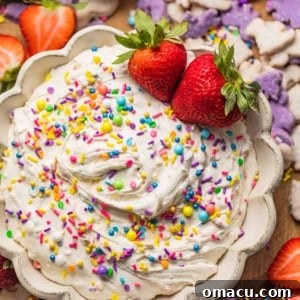 Dunkaroo dip in a bowl garnished with rainbow sprinkles and strawberries, a perfect party dessert.