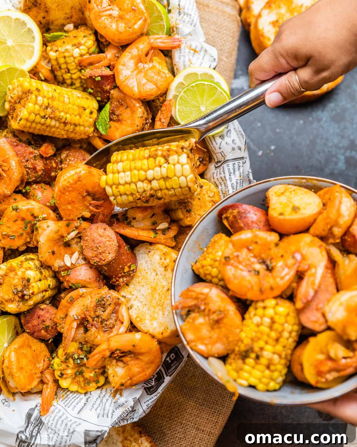 a hand scooping out seafood out of a low country boil and placing it into a bowl.