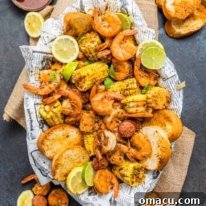low country boil in a oval platter on top of newspaper surrounded by shrimp and sliced bread.