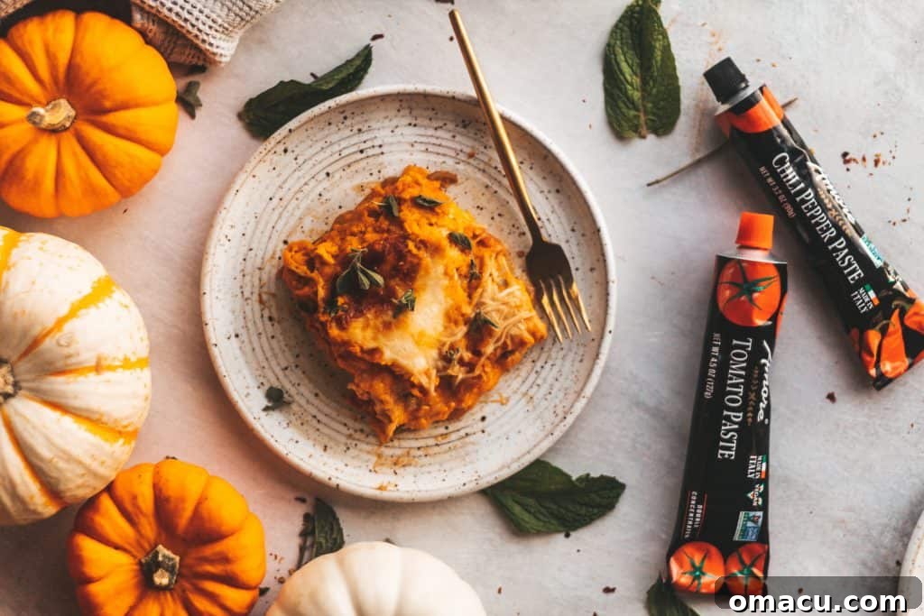 A delicious slice of pumpkin lasagna plated with tubes of Amore tomato paste in the background.