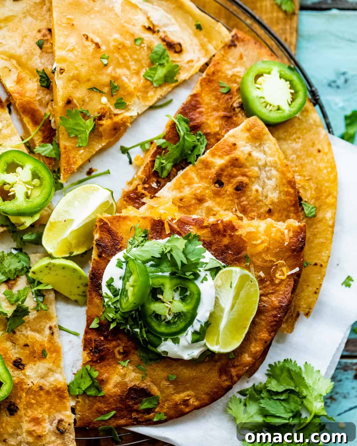 sliced cheese quesadilla with sour cream and jalapenos on top.