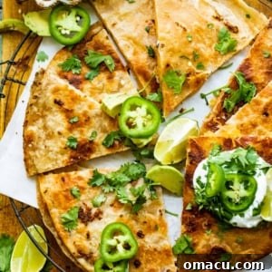 cheese quesadilla on a cooling rach garnished with jalapeno, cilantro, and sour cream.