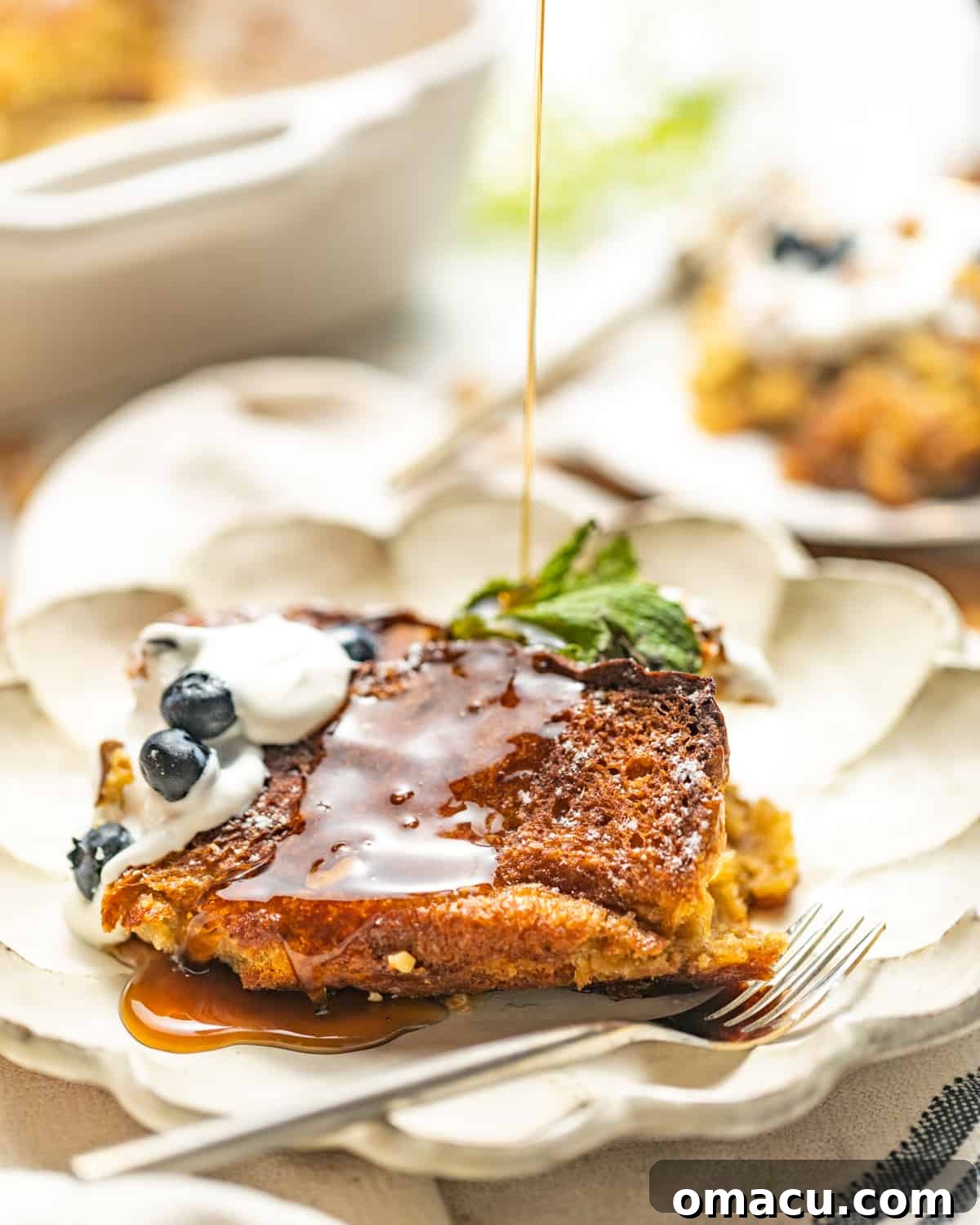 Golden-brown brioche French toast casserole drizzled with warm maple syrup and topped with fresh berries, ready to serve.
