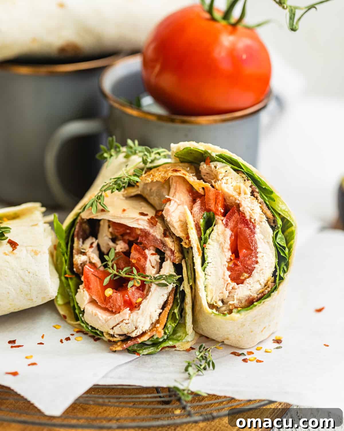 Delicious chicken bacon ranch wrap cut in half, showcasing its flavorful layers on parchment paper.