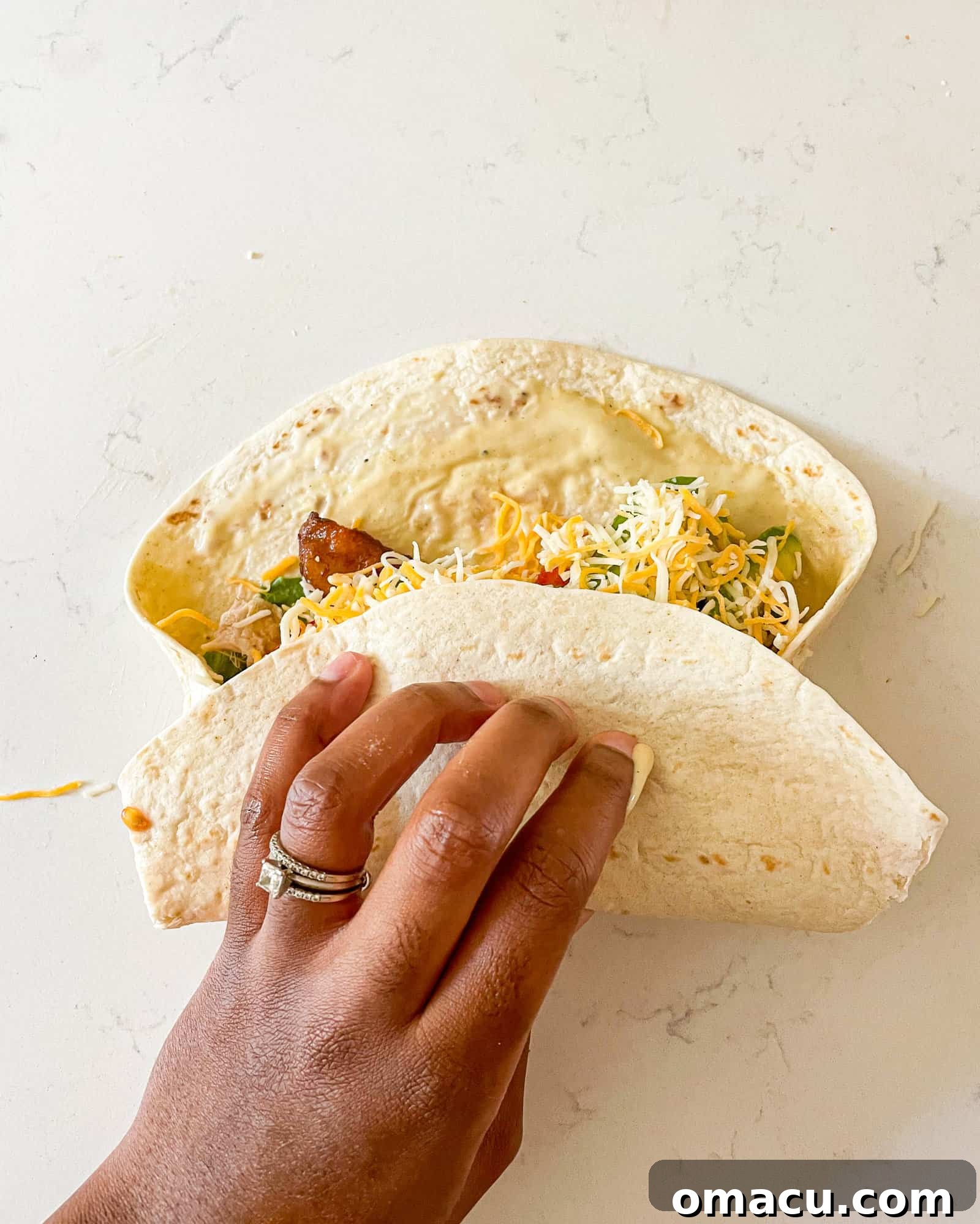 Demonstration of folding a tortilla into a wrap, showing the sides tucked in before rolling.
