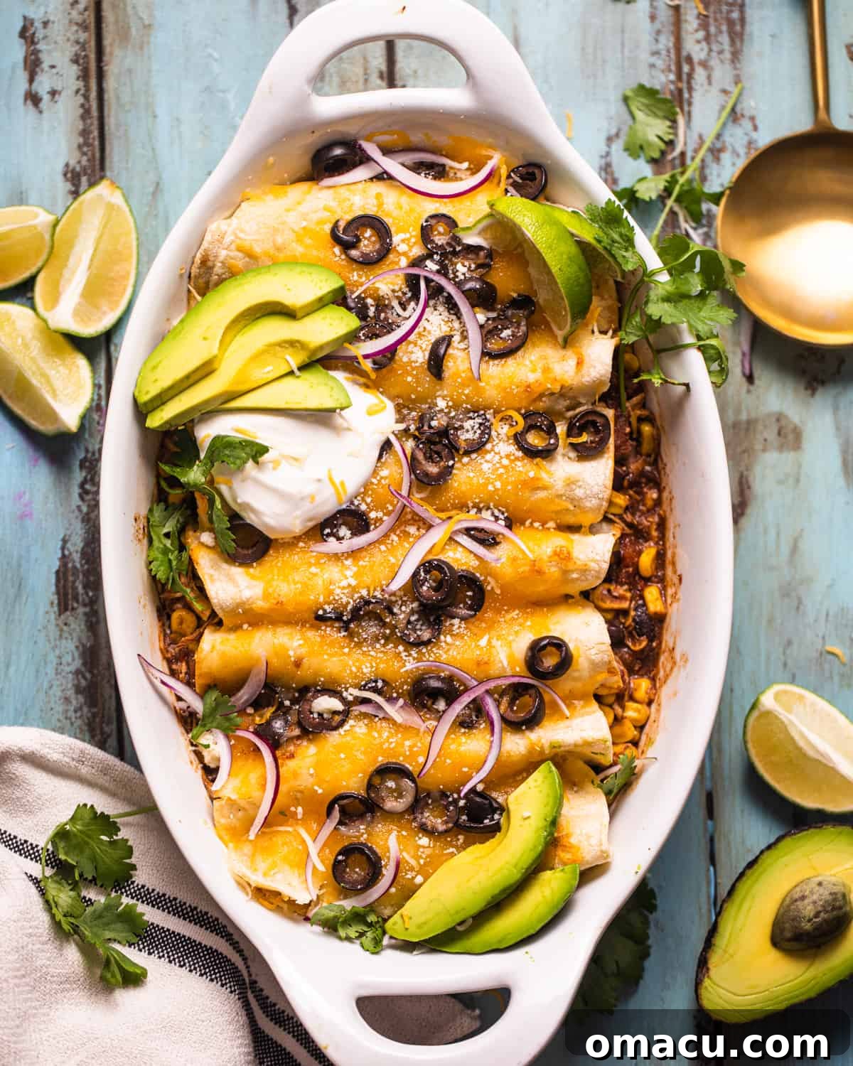 Delicious chicken enchiladas in a casserole dish garnished with sour cream, fresh avocado slices, and black olives, ready to be served.