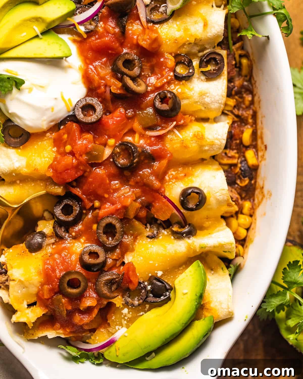 A close-up, mouth-watering photo of slow cooker chicken enchiladas in a casserole dish, highlighting the melted cheese and rich filling.