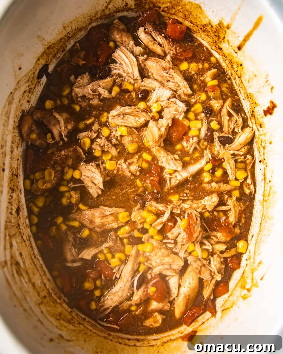 Perfectly shredded chicken resting in a crockpot after slow cooking, moist and tender.