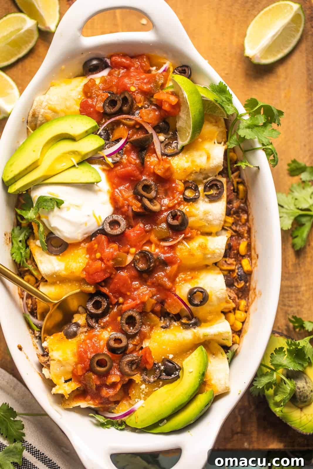 A serving of slow cooker chicken enchiladas in a casserole dish, beautifully garnished with fresh salsa, creamy sour cream, finely chopped red onion, and slices of ripe avocado.