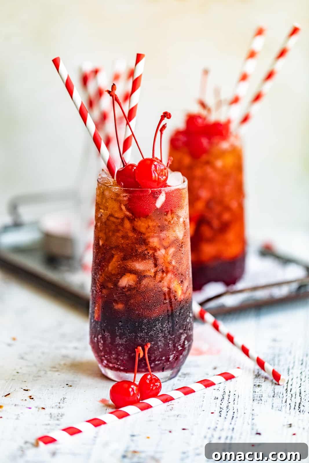 A single Roy Rogers drink presented on a serving tray, adorned with crushed ice and bright red cherries, emphasizing its refreshing appeal.
