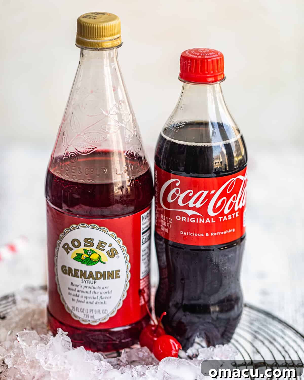 The essential ingredients for a Roy Rogers drink: a classic bottle of Coca-Cola, a bottle of rich grenadine syrup, and a jar of glistening maraschino cherries.