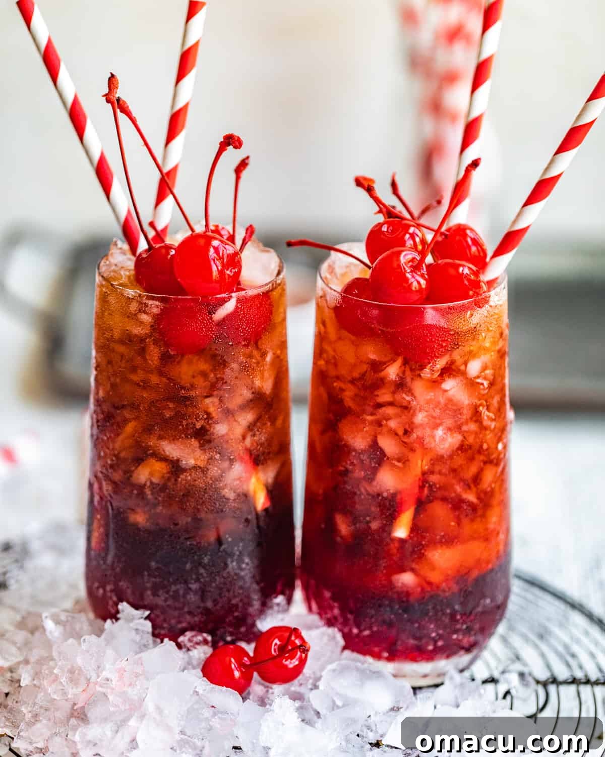 Two vibrant Roy Rogers drinks served in glasses filled with crushed ice, showcasing their beautiful color and traditional garnishes.