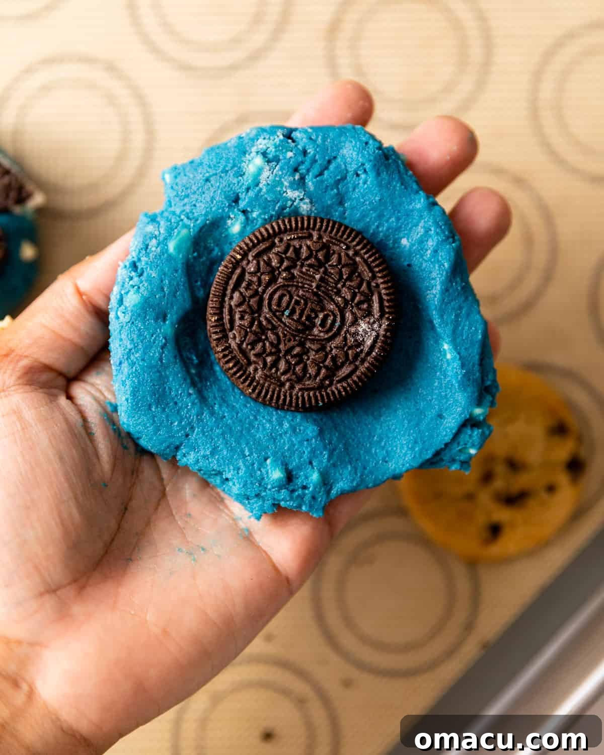 An Oreo cookie carefully placed inside the flattened cookie dough disc, the first layer of stuffing.