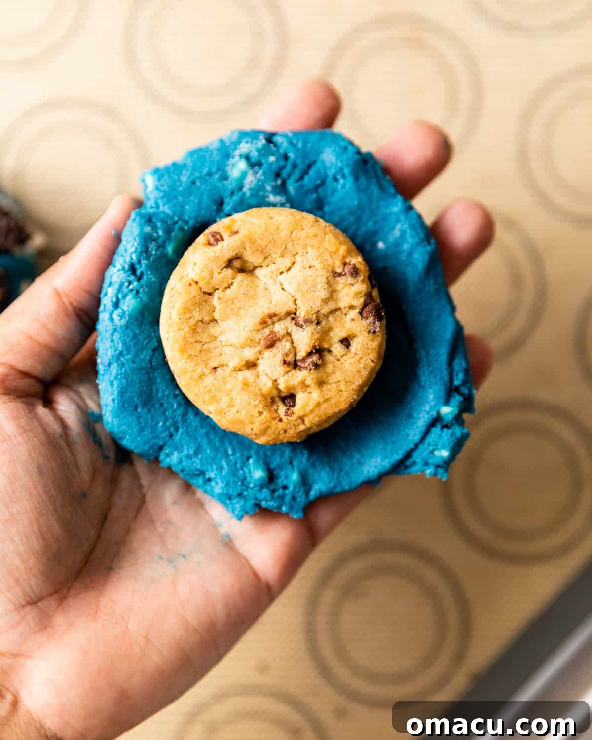 A chocolate chip cookie placed on top of the Oreo cookie inside the dough, completing the stuffed center.
