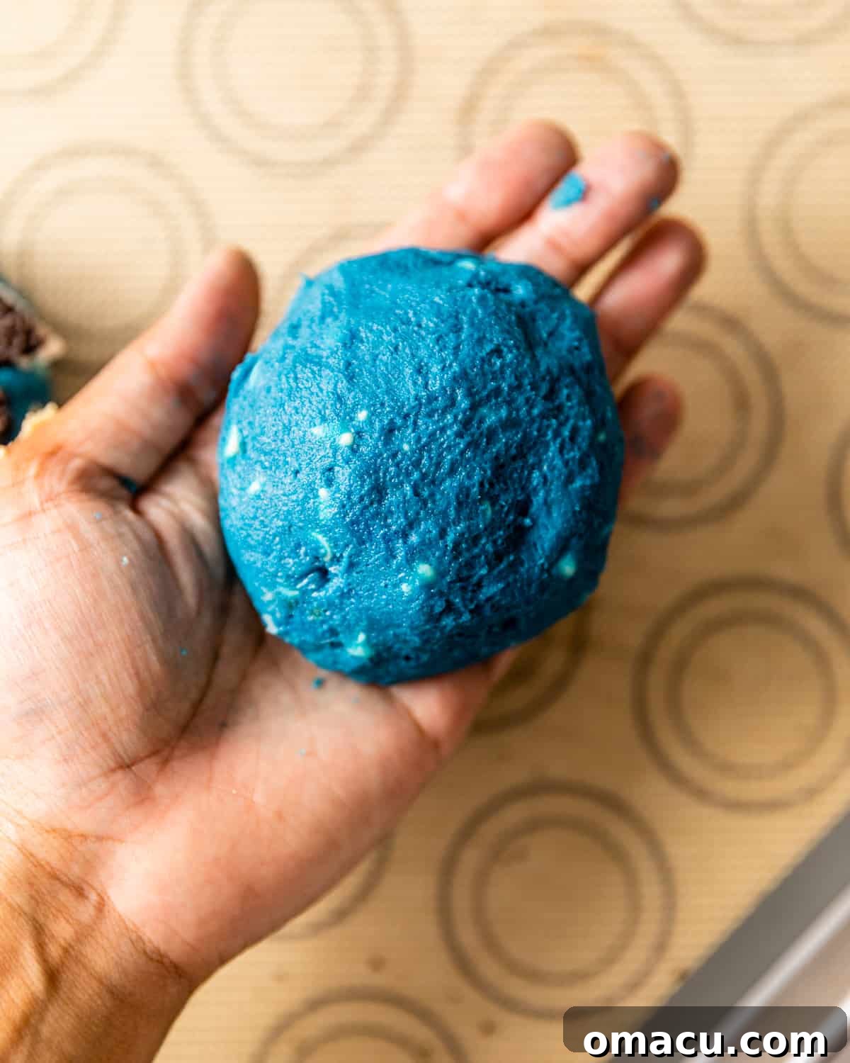 A perfectly molded Cookie Monster cookie dough ball on a cookie sheet, ready for refrigeration.