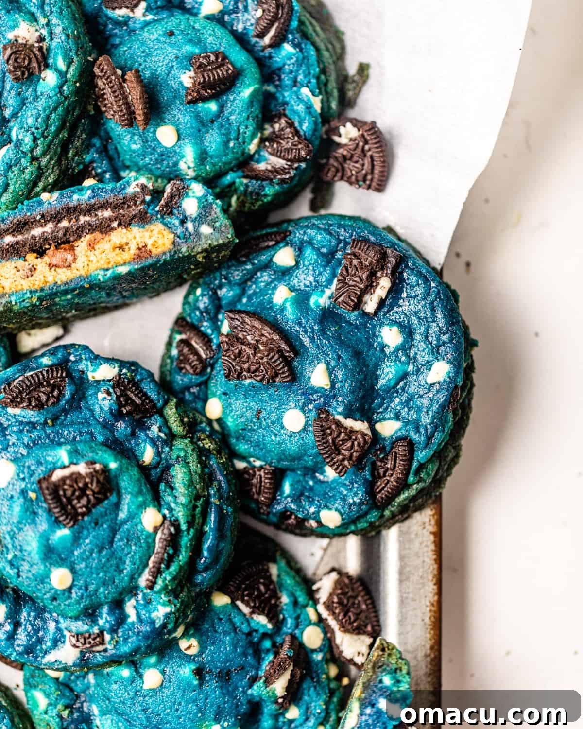 Close-up of a vibrant blue monster cookie resting on parchment paper, ready to be enjoyed.