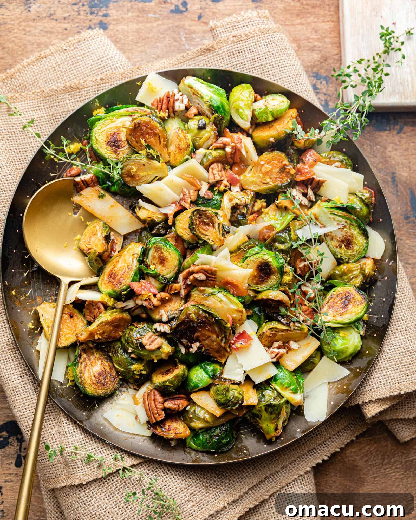 Close-up of roasted brussels sprouts and bacon coated in a glossy honey sriracha sauce in a serving bowl, with a spoon.