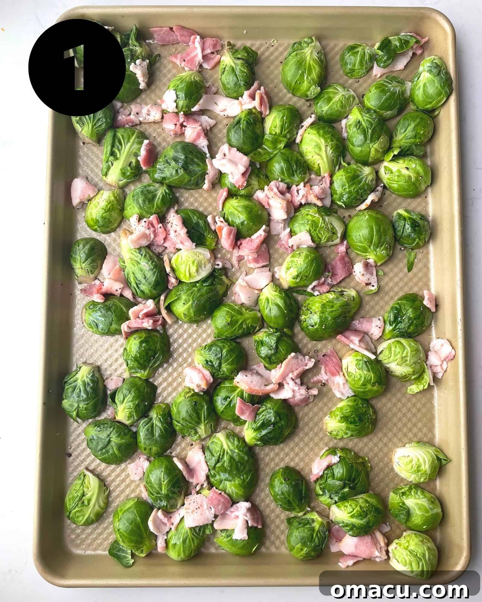 Halved brussels sprouts and chunks of bacon arranged on a baking sheet, ready for roasting.