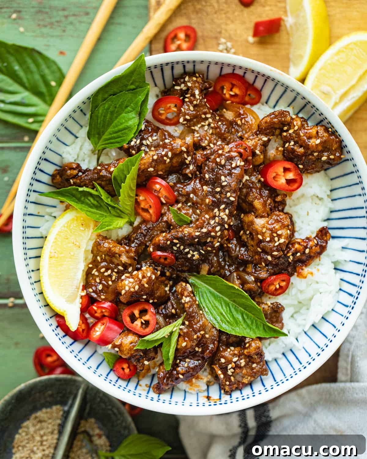 Crispy Chilli Beef in a bowl garnished with sesame seeds and fresh herbs, ready to be served.