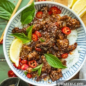Crispy Chilli Beef in a bowl garnished with sesame seeds and fresh herbs.