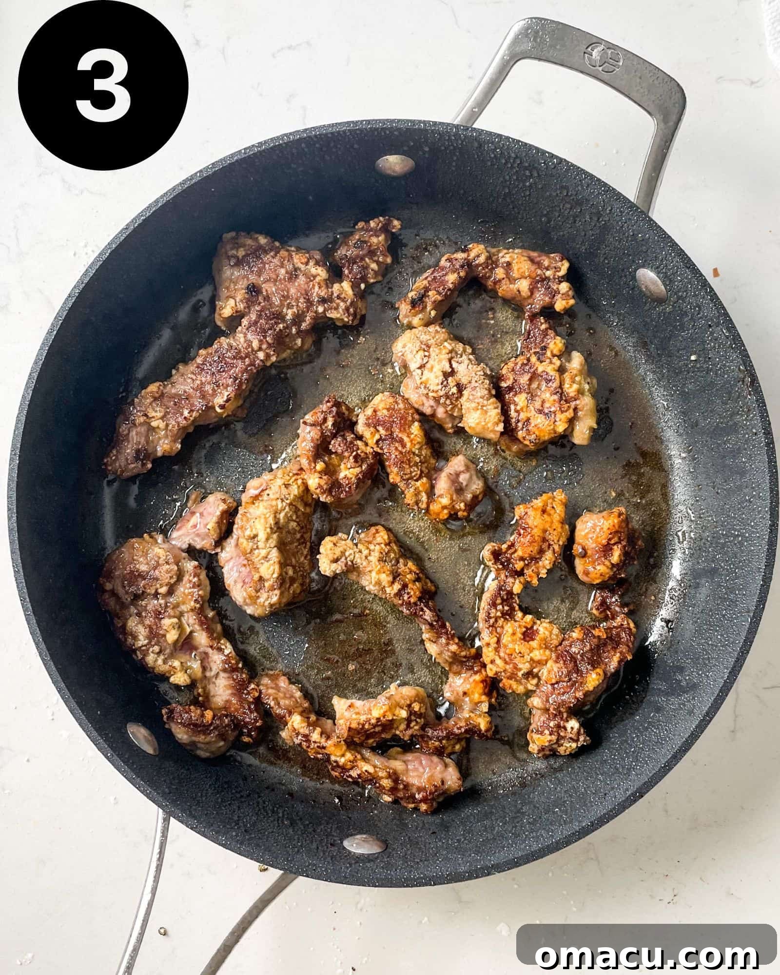 Golden-brown fried steak strips sizzling in a hot frying pan.