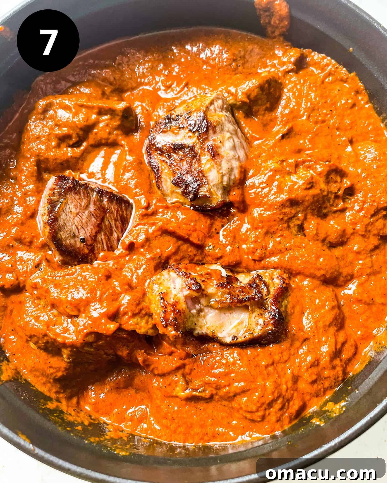 birria consume poured on top of the seared chuck roast, ready for simmering.