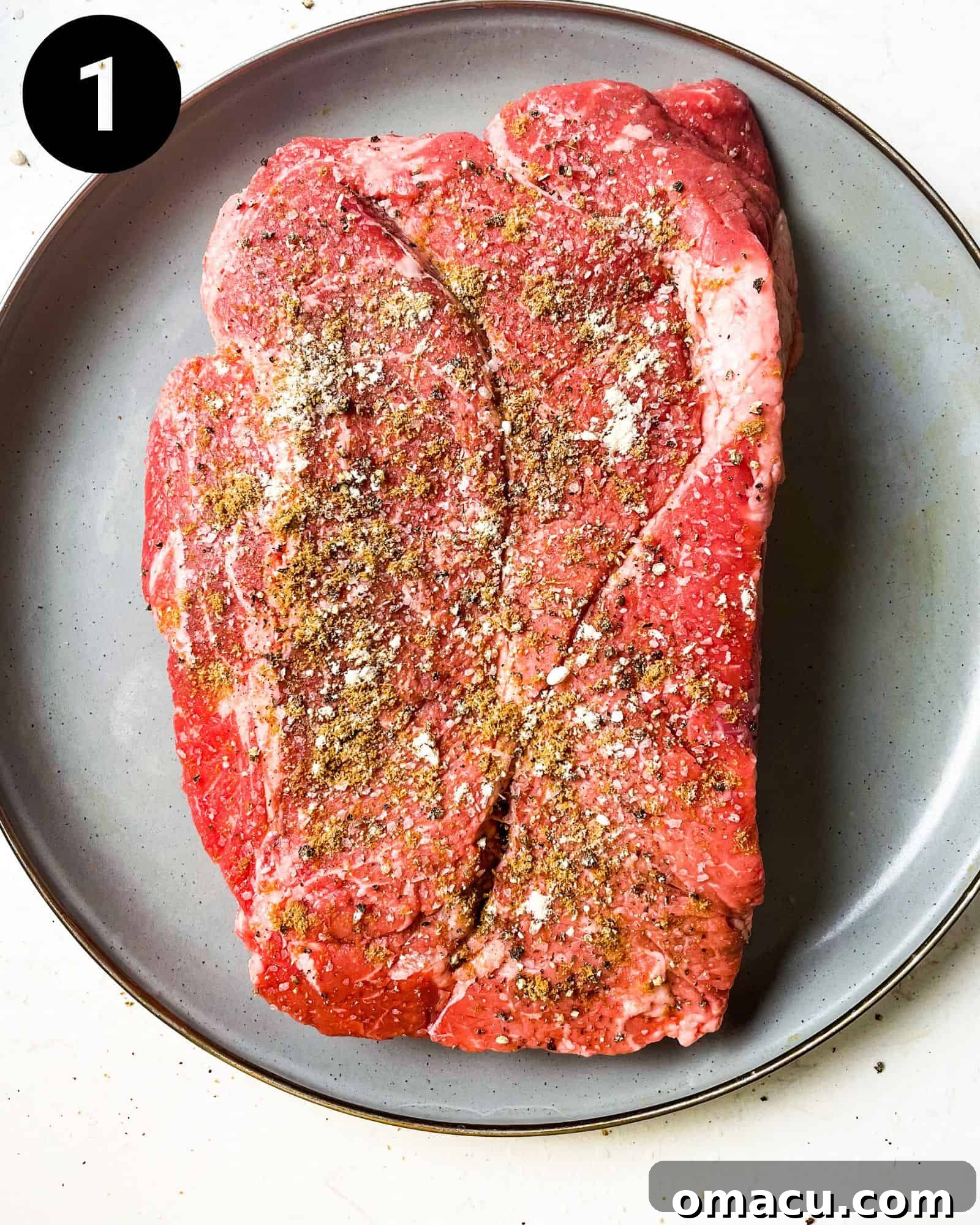 seasoned chuck roast on a plate, ready for searing.