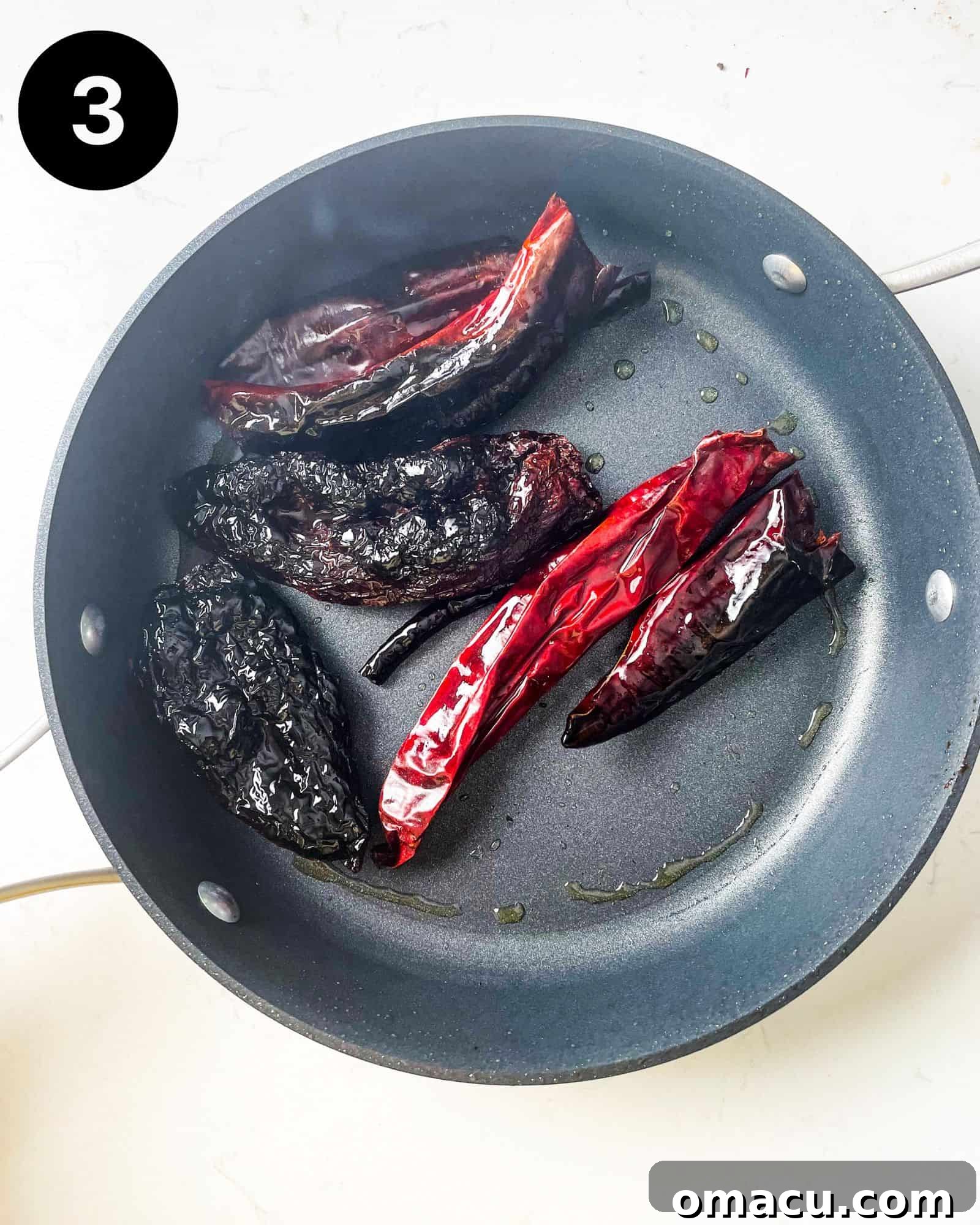 Chili peppers toasted in a pan, achieving a slight char.