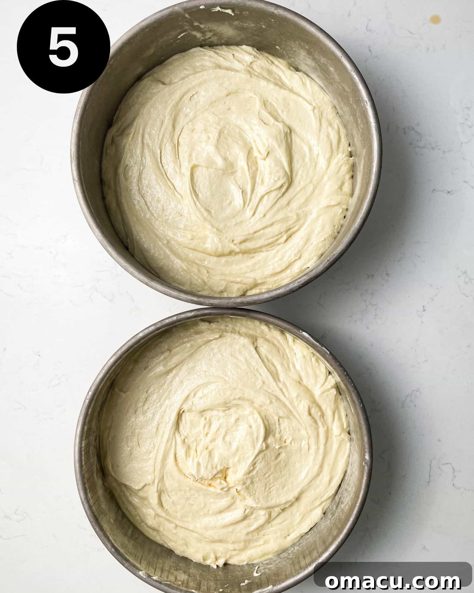 cake batter divided into two 9-inch baking pans, ready for the oven.