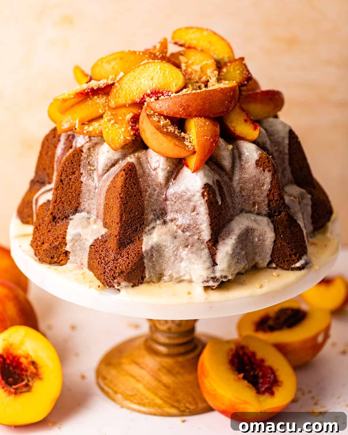 a peach cobbler pound cake on a cake stand topped with roasted peaches.