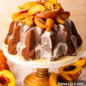 a peach cobbler pound cake on a cake stand topped with roasted peaches.