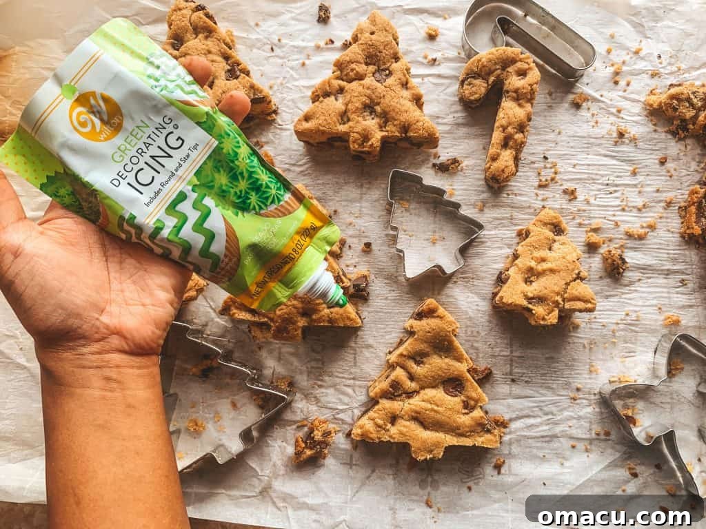 Applying green icing in zig-zag lines to a cut-out Christmas tree cookie
