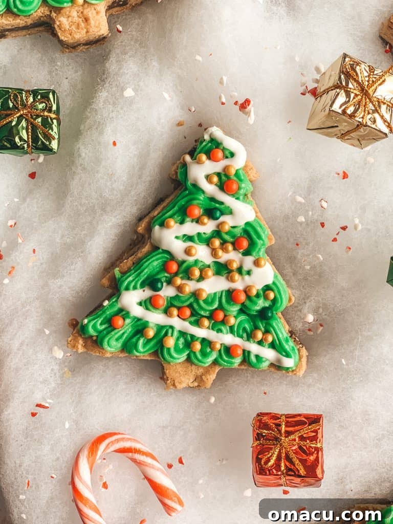 Fully decorated Christmas tree cookies with green icing, pearl sprinkles, and garland designs