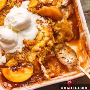peach cobbler in a baking dish with a spoon.