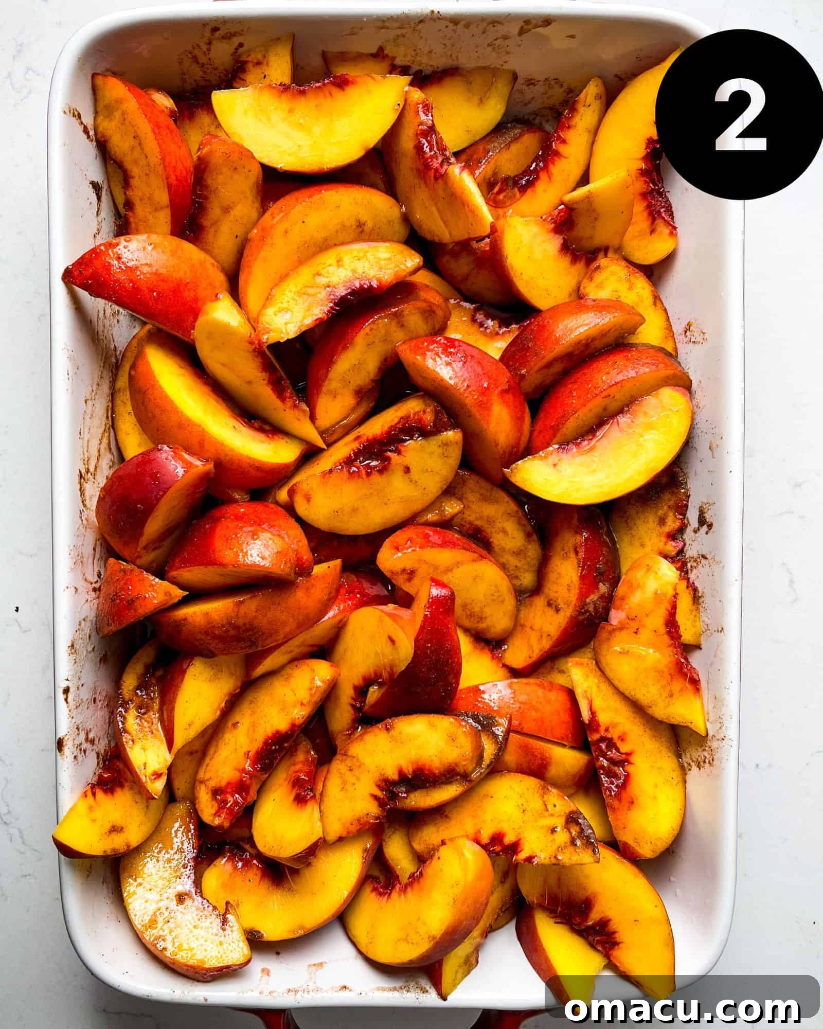 The seasoned yellow peaches, now ready, are evenly spread in a 9x13 inch baking dish before the topping is added.