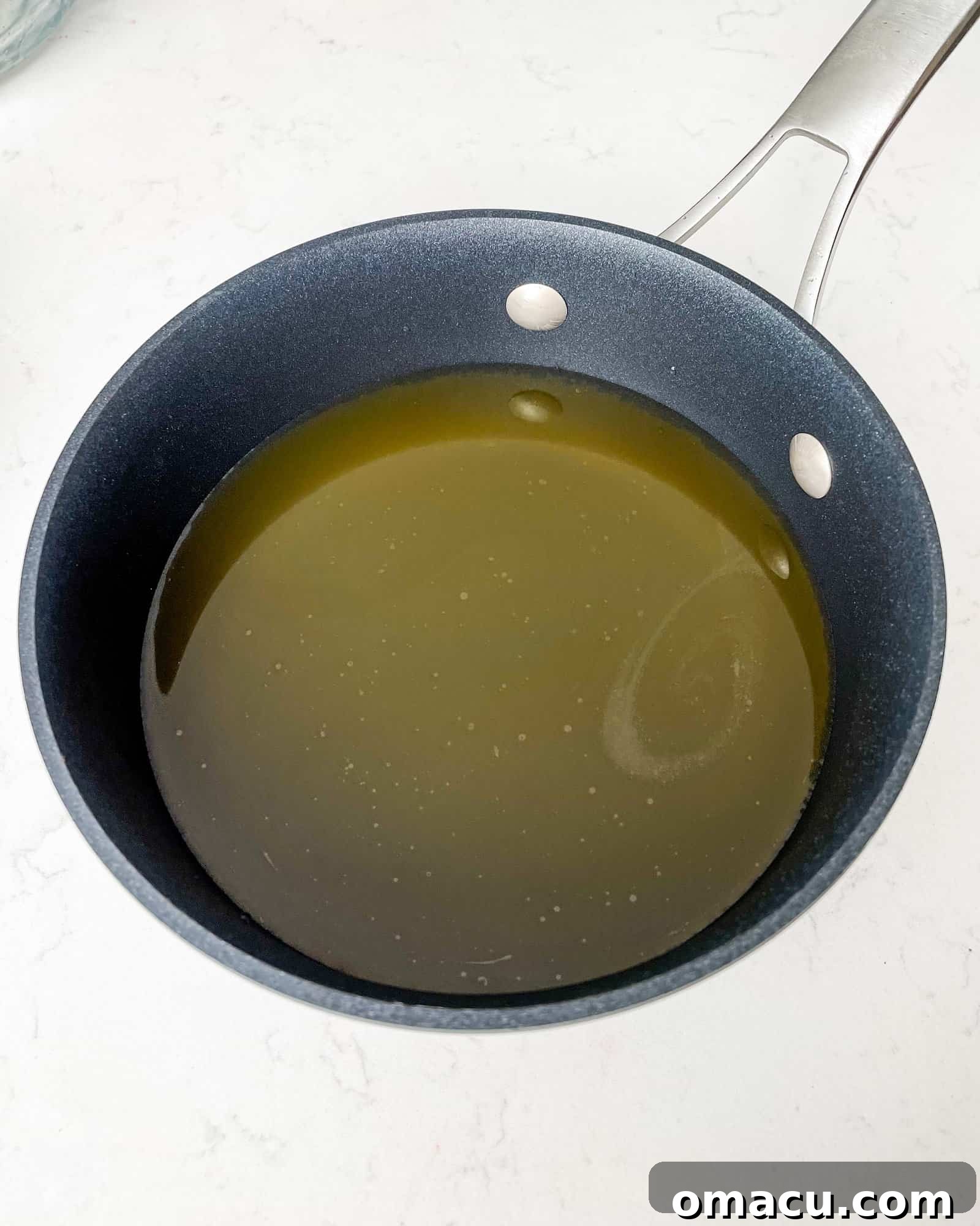 Chicken broth simmering in a sauce pan.