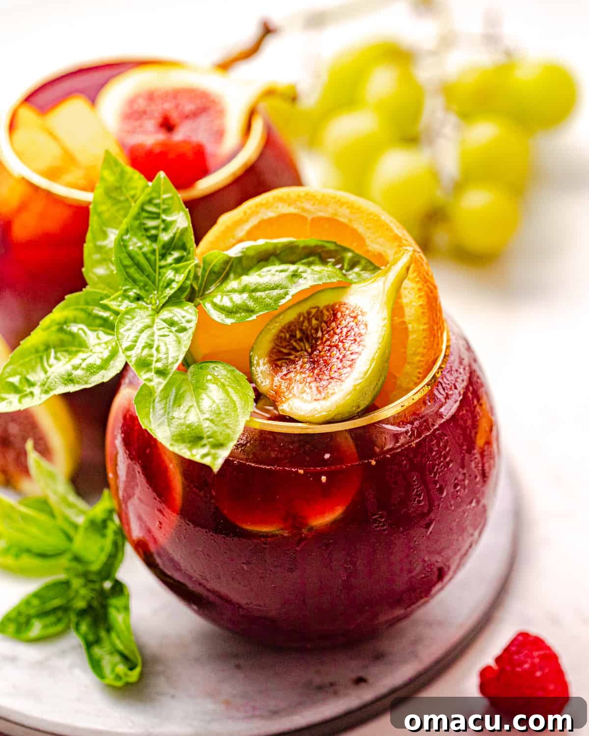 A glass of sparkling bourbon sangria adorned with fresh figs, fragrant basil, and vibrant orange slices, ready to be enjoyed.