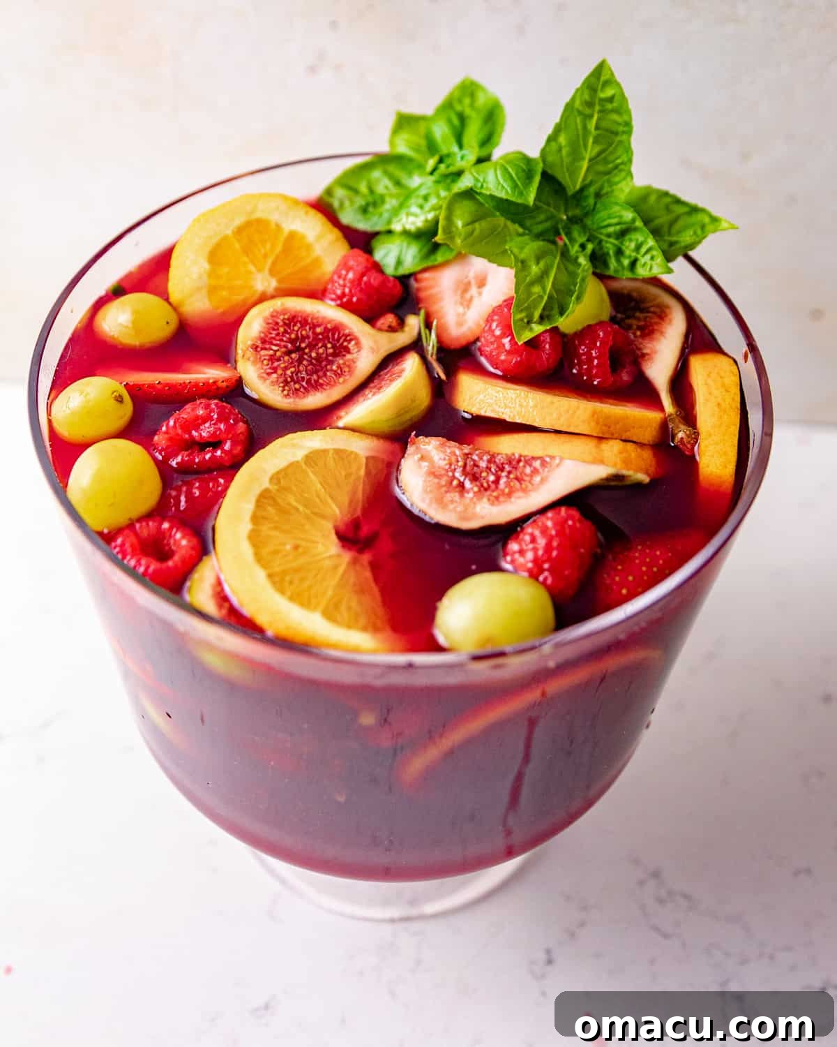 A large pitcher brimming with vibrant sangria, exquisitely garnished with fresh basil leaves, ready to be poured.